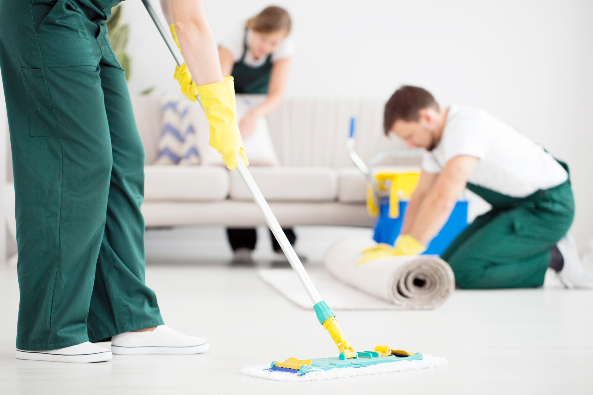 cleaner,in,green,overalls,cleaning,the,floor,using,a,mop
